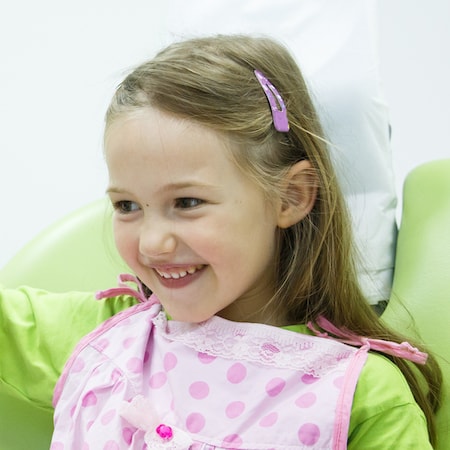 Little girl wearing a pink bib during her children's dentistry visit