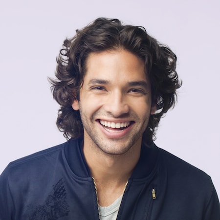 Smiling man with curly hair wearing a black jacket, representing patient satisfaction and comfort in dental care at the Dental Group of Westchester.