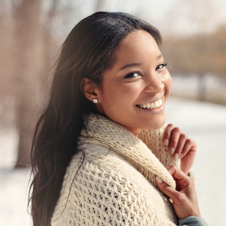 Smiling woman in a cozy sweater, showcasing a healthy smile, reflecting confidence in dental care and oral health.