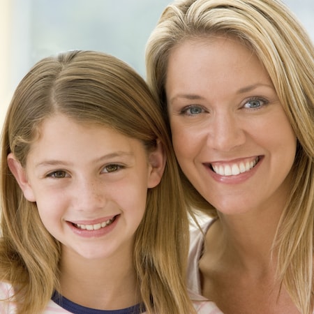 Light-haired mother and daughter smiling 