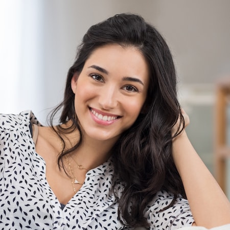 Dark haired lady leaning on her hand and smiling