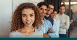 Five dental implant candidates in a diagonal line smiling at the camera
