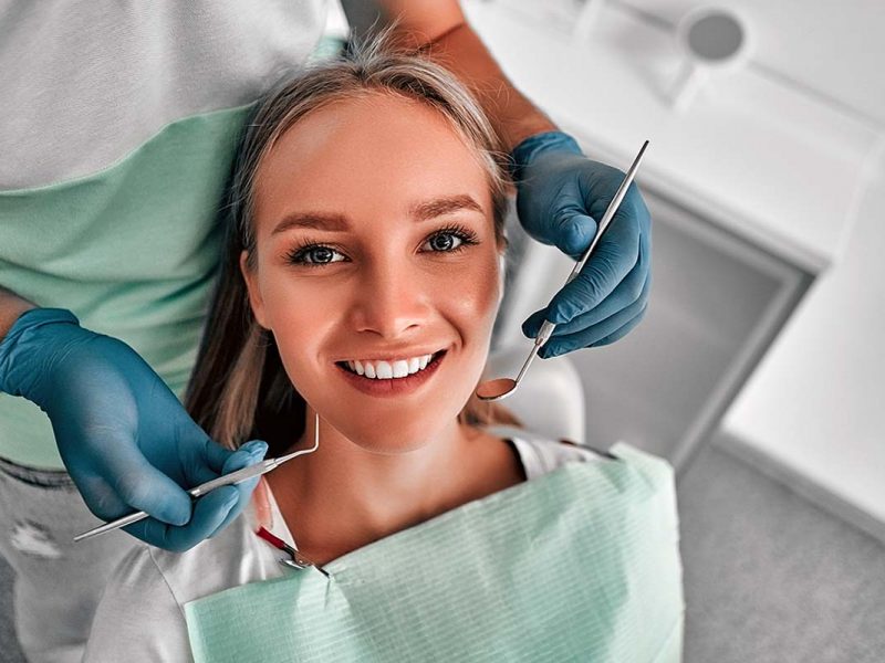 A young girl getting teeth checked with a dental mirror.