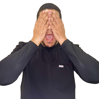 Julio Rosario, dental assistant at Dental Group of Westchester, playfully covering his face with hands, expressing excitement or surprise.