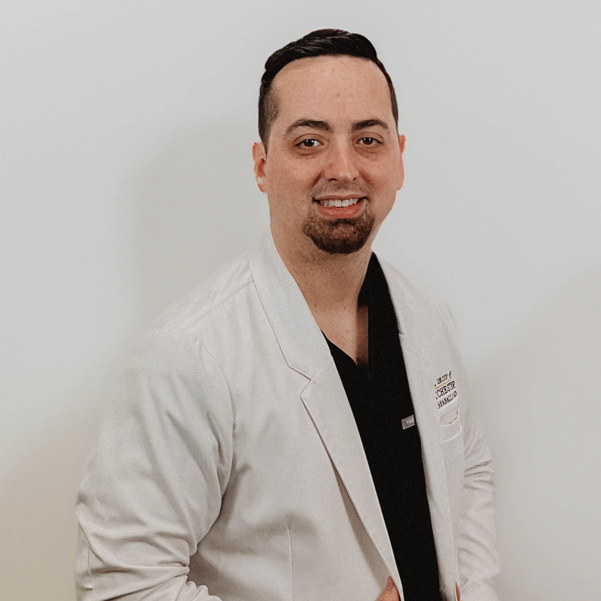 Dr. James Ramos, board-certified periodontist and dental implant surgeon, wearing a white lab coat, smiling against a neutral background.