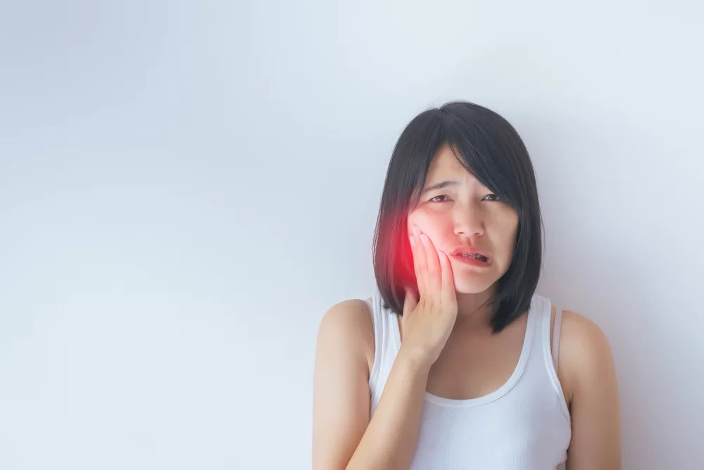Woman experiencing severe jaw pain, holding her face, indicating dental distress, relevant to emergency dental care services near White Plains, NY.