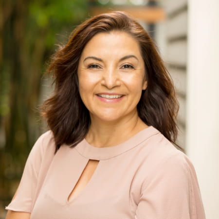 Smiling woman in a light blouse, representing patient satisfaction in restorative dentistry at Dental Group of Westchester.