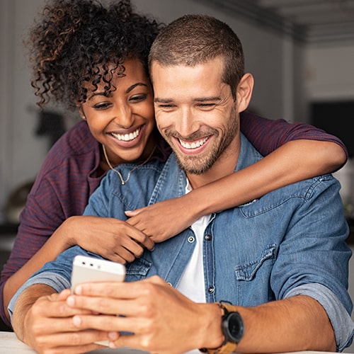 A couple smiling and looking at a phone.