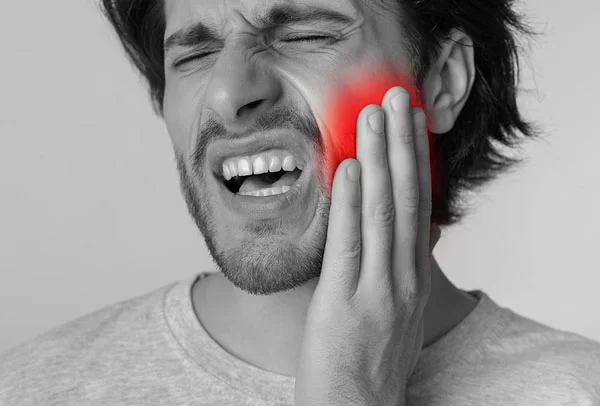 Man experiencing severe tooth pain, holding his jaw in distress, with a highlighted area indicating discomfort, emphasizing the need for urgent dental care.