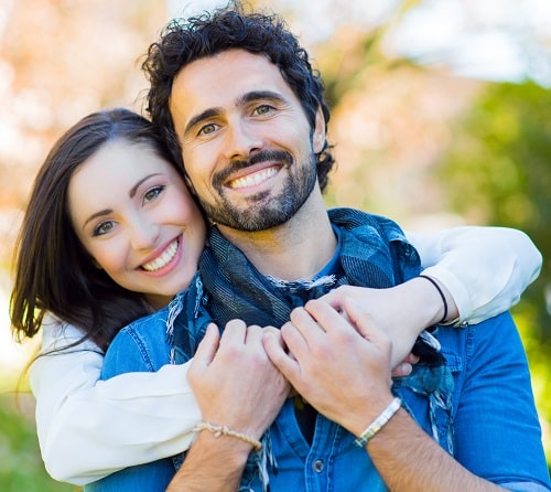 Smiling couple embracing outdoors, representing comfort and support, relevant to emergency dental care services at Dental Group of Westchester.