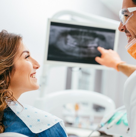 Patient smiling at dentist discussing digital x-ray results in a family dental practice setting.